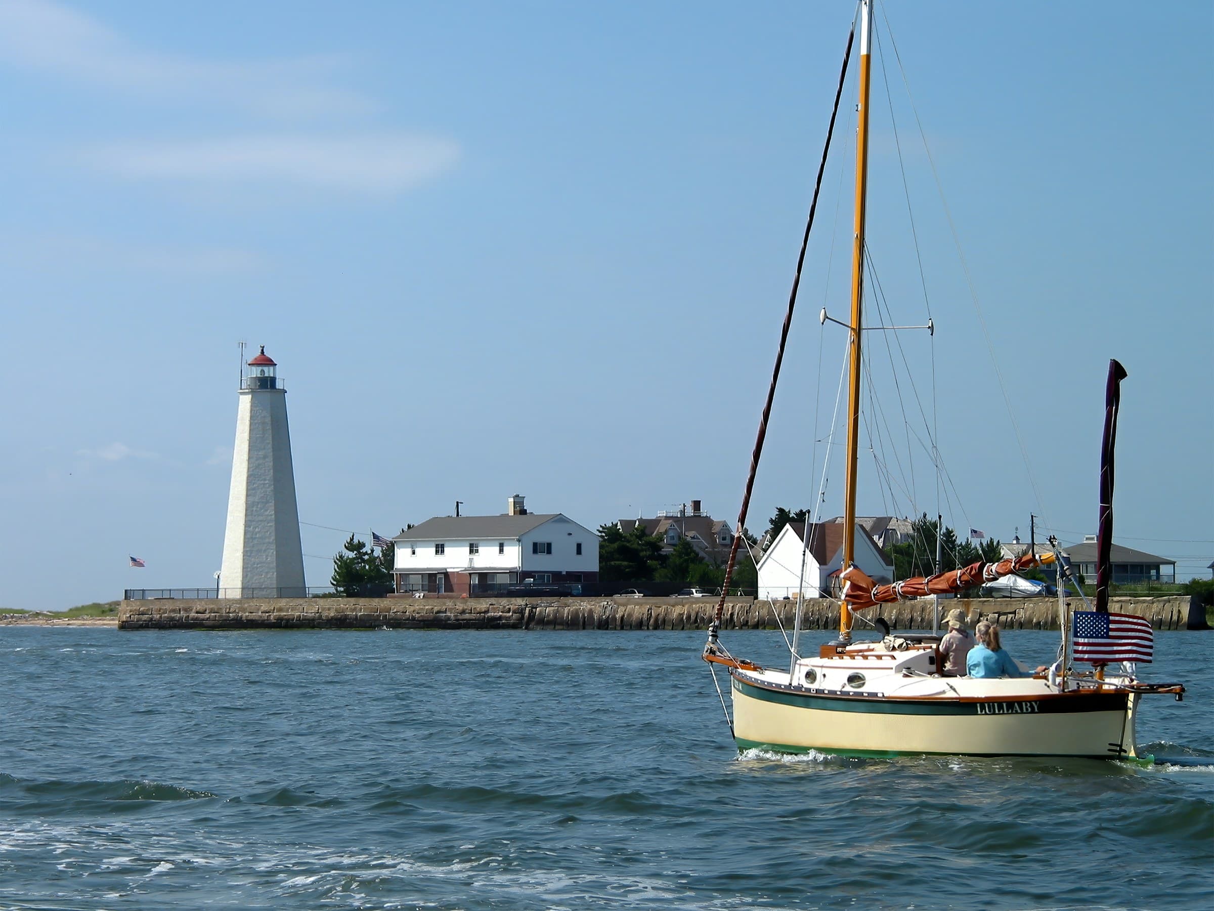 Lynde Point Lighthouse and a sailboat at the mouth of the Connecticut River.